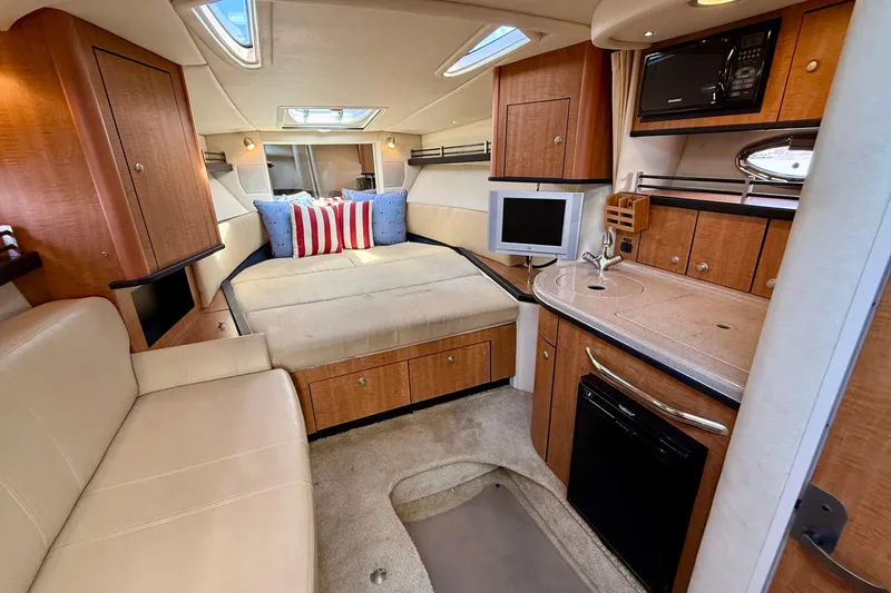 Slide: The Image of 2006 Sea Ray 290 Sundancer cabin interior with cozy seating, kitchenette, and modern amenities. - 5
