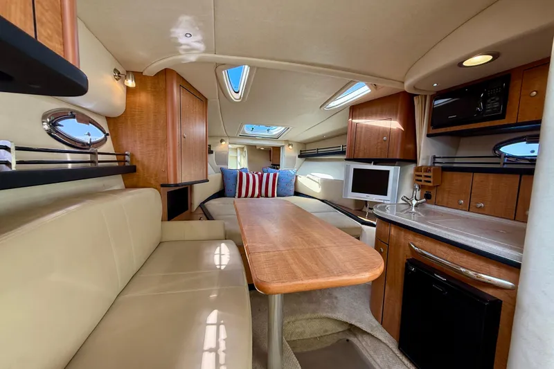 Slide: The Image of 2006 Sea Ray 290 Sundancer cabin interior with seating, kitchenette, and entertainment area. - 6