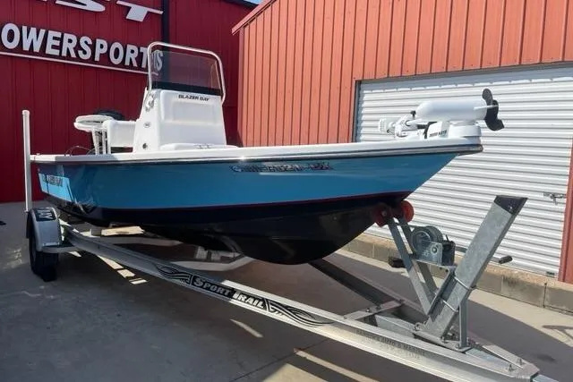 Slide: The Image of Blue Blazer Bay 1960 boat on trailer, parked outside a red building, 2016 model. - 0