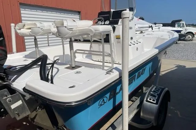 Slide: The Image of 2016 Blazer Bay 1960 boat on trailer, parked near a red building. - 2