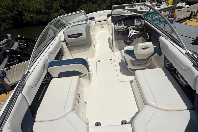 Slide: The Image of 2016 Chaparral 230 Suncoast boat interior with seating and helm, docked by water. - 20