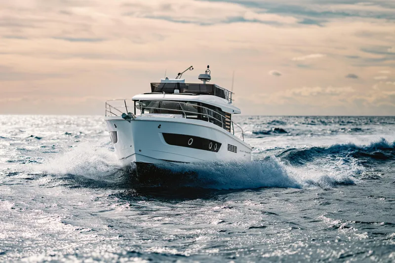 Slide: The Image of 2026 Beneteau Swift Trawler 37 cruising through ocean waves at sunset. - 16