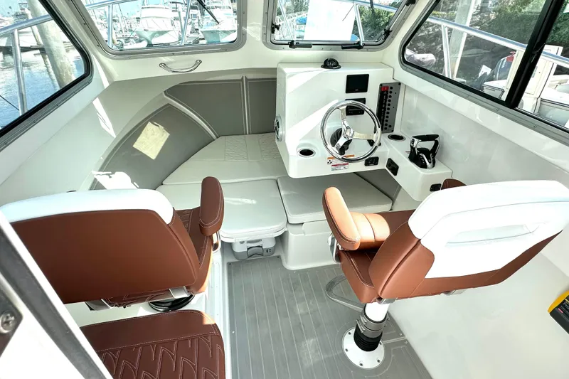 Slide: The Image of 2025 Parker 2420 Sport Cabin interior with brown seats and modern steering console. - 4