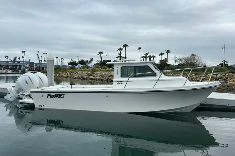 The Image of 2025 Parker 2420 Sport Cabin boat docked in a marina, featuring sleek design and twin engines. - 1