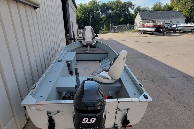 Slide: The Image of 2014 MirroCraft 1400 boat with outboard motor, parked outdoors near other boats. - 18