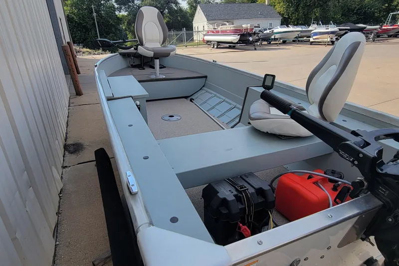 Slide: The Image of 2014 MirroCraft 1400 boat with seating and motor, parked near other boats. - 20