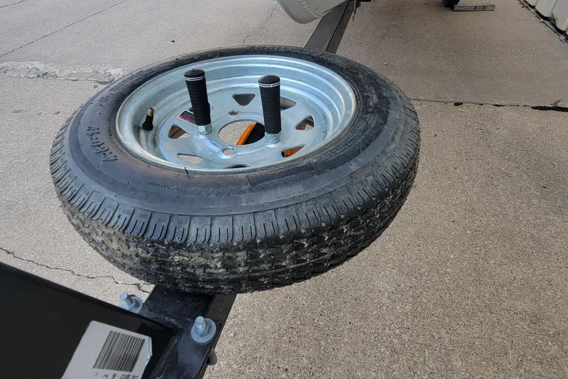 Slide: The Image of Spare tire mounted on a MirroCraft 1400 trailer, 2014 model, on concrete surface. - 3