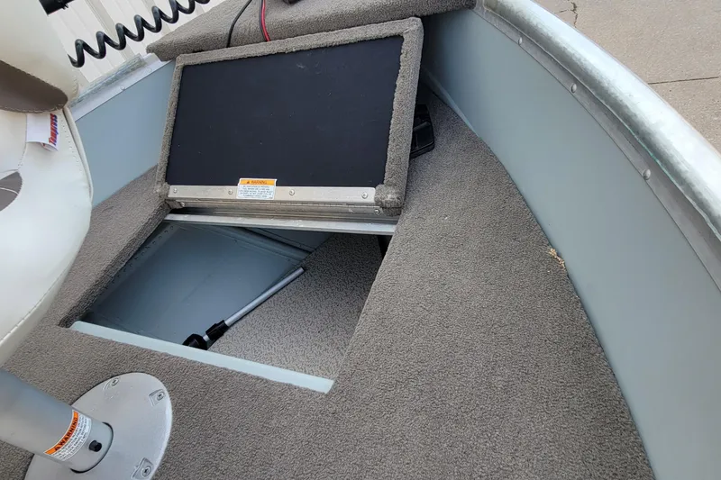 Slide: The Image of 2014 MirroCraft 1400 boat interior with open storage compartment and carpeted floor. - 9