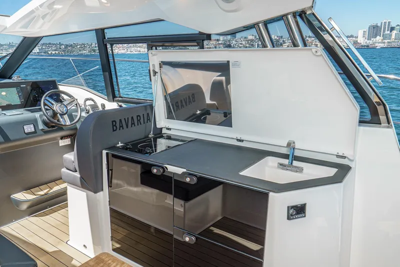 Slide: The Image of 2024 Bavaria SR38 yacht interior with sleek kitchen and steering area, overlooking the ocean. - 24