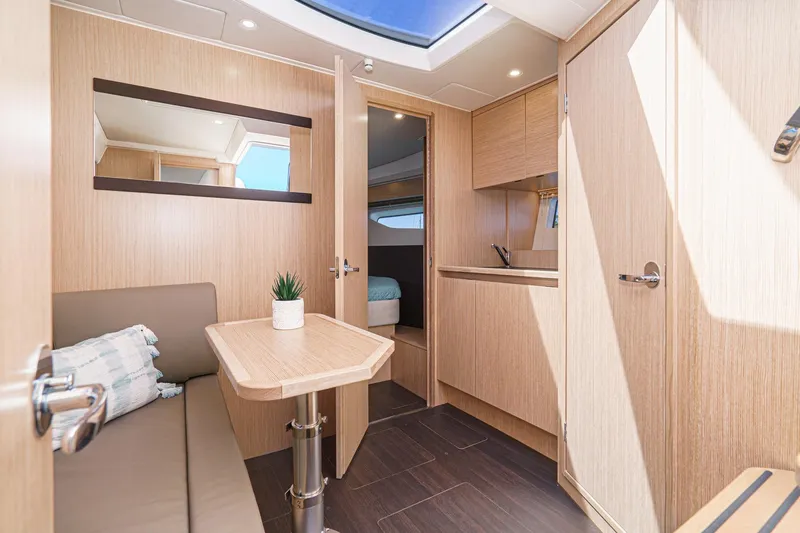 Slide: The Image of 2024 Bavaria SR38 yacht interior with modern wood finish, skylight, and compact dining area. - 35