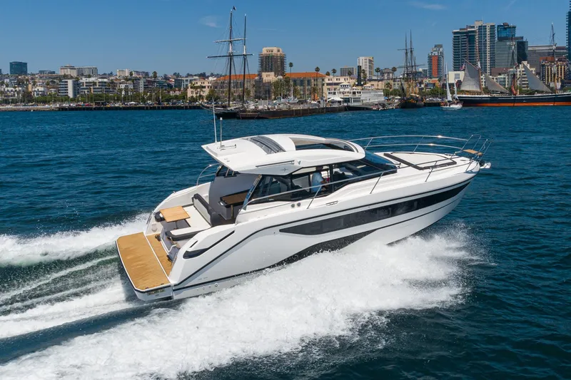 Slide: The Image of 2024 Bavaria SR38 yacht cruising in a vibrant city harbor under a clear blue sky. - 7