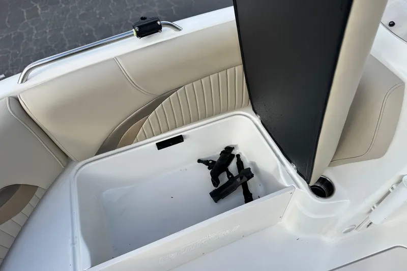 Slide: The Image of 2013 NauticStar 203 SC boat seat storage compartment with beige upholstery and cup holder. - 16