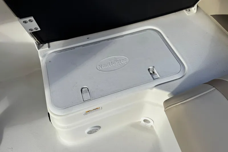 Slide: The Image of 2013 NauticStar 203 SC boat storage compartment with logo on lid. - 23