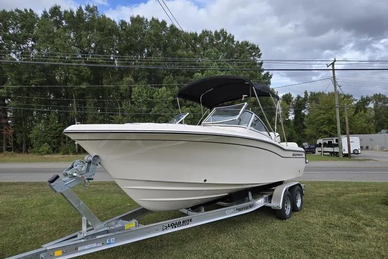 Slide: The Image of 2026 Grady-White Freedom 215 boat on trailer, parked on grass with trees in background. - 23