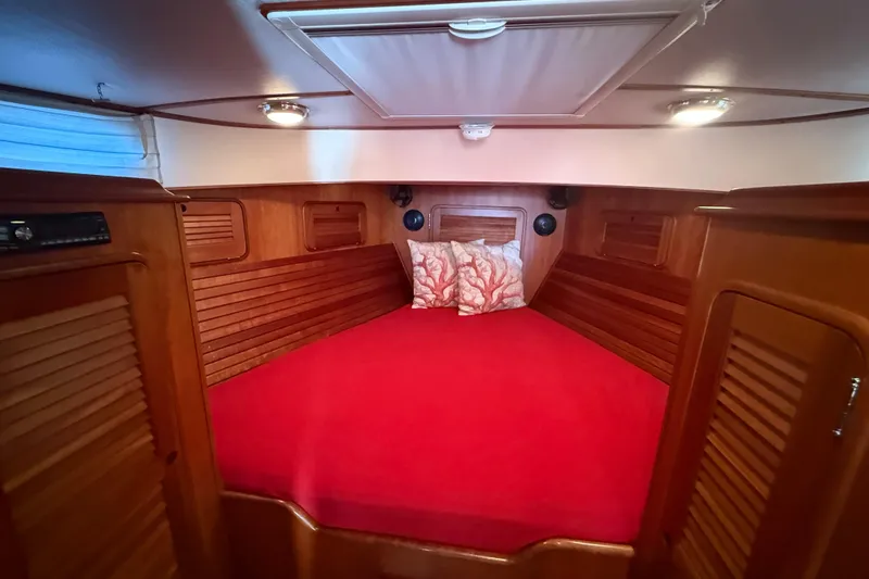 Slide: The Image of Cozy cabin interior of 2003 Hinckley Talaria 40 with red bedding and wooden finish. - 12