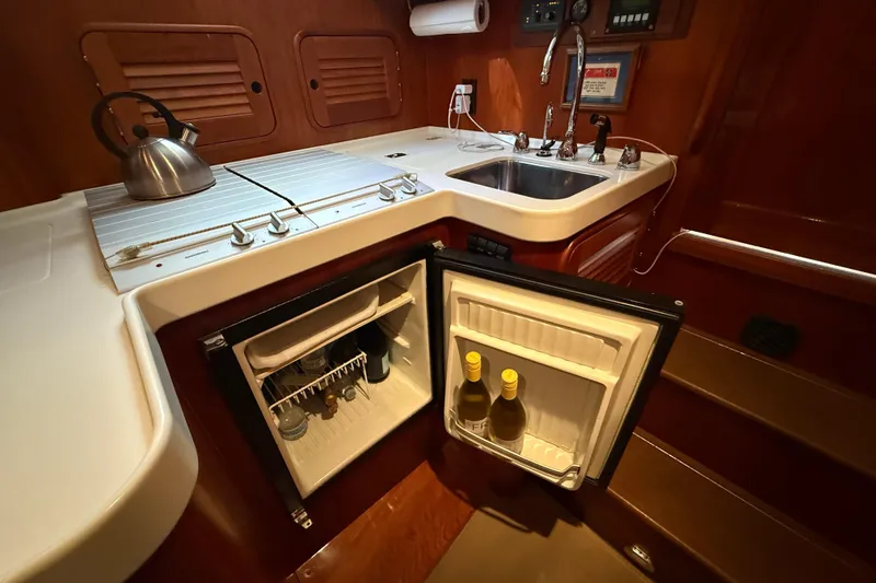 Slide: The Image of 2003 Hinckley Talaria 40 yacht kitchen with sink, stove, and open fridge. - 16