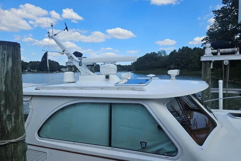 Slide: The Image of 2003 Hinckley Talaria 40 yacht docked by a serene lake under a blue sky. - 21
