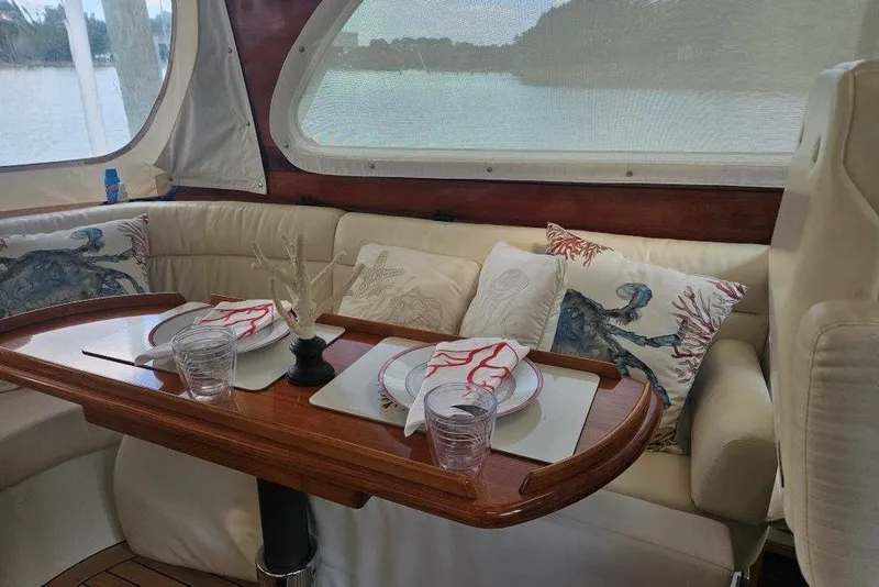 Slide: The Image of Luxurious 2003 Hinckley Talaria 40 yacht interior with elegant dining setup and coastal-themed decor. - 4