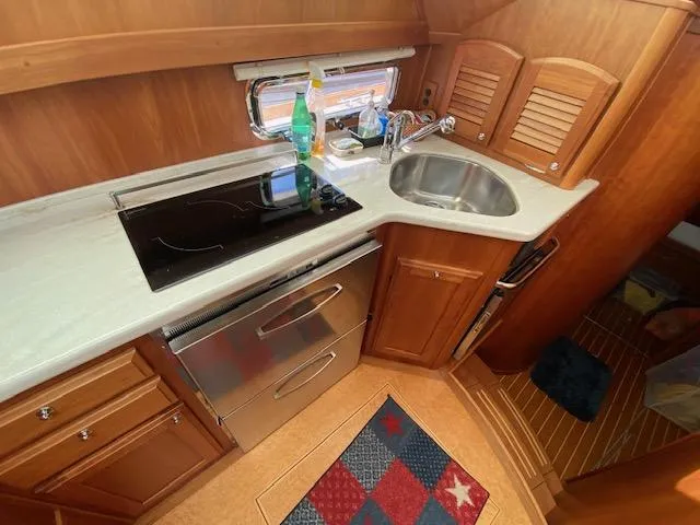 Slide: The Image of 2015 Sabre 42 Salon Express galley with stove, sink, and wooden cabinetry. - 26