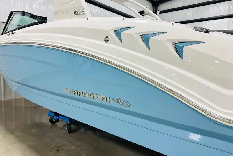 Slide: The Image of 2025 Chaparral 23 SSi OB boat with sleek blue and white design in showroom. - 7