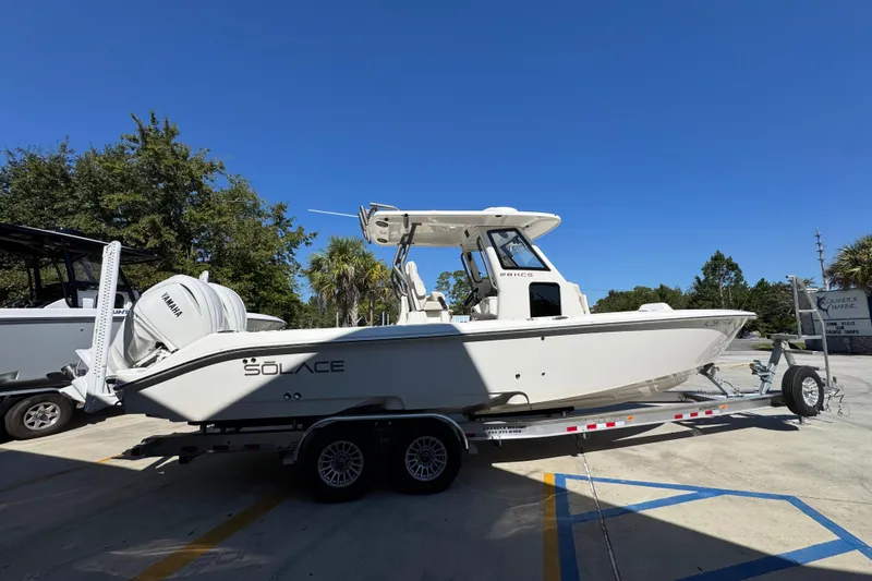 Slide: The Image of 2025 Solace 28 HCS boat on trailer, featuring Yamaha engine, parked outdoors. - 10