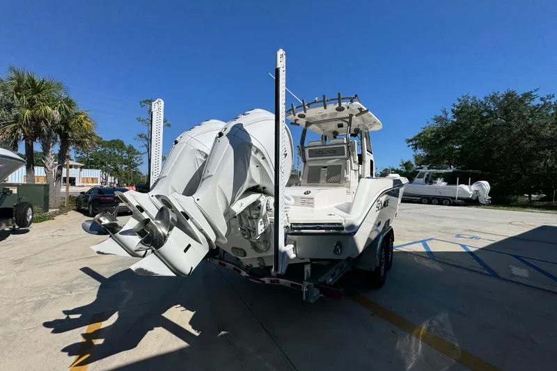 Slide: The Image of 2025 Solace 28 HCS boat with dual outboard engines on a trailer, sunny day. - 12
