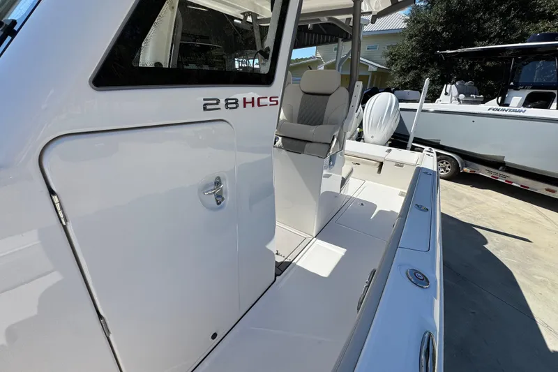 Slide: The Image of 2025 Solace 28 HCS boat, sleek design, white exterior, modern seating, docked outdoors. - 22