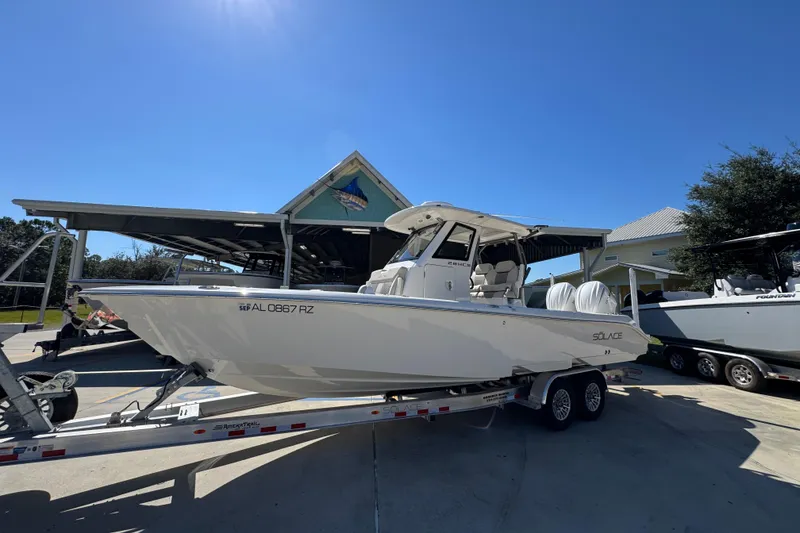 Slide: The Image of 2025 Solace 28 HCS boat on trailer, parked outdoors under clear blue sky. - 3