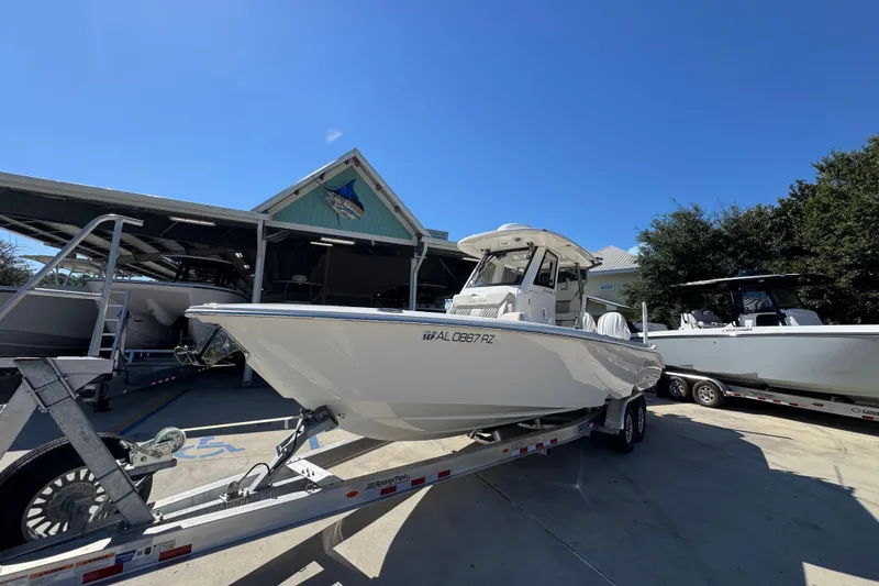 Slide: The Image of 2025 Solace 28 HCS boat on trailer, parked outside a marina under clear blue sky. - 4