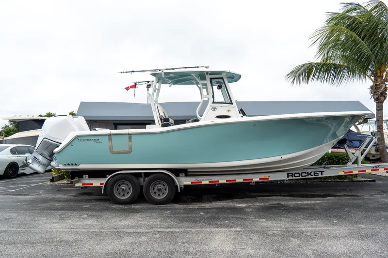 The Image of 2022 Tidewater 292 CC Adventure boat on trailer, parked near palm tree. - 2