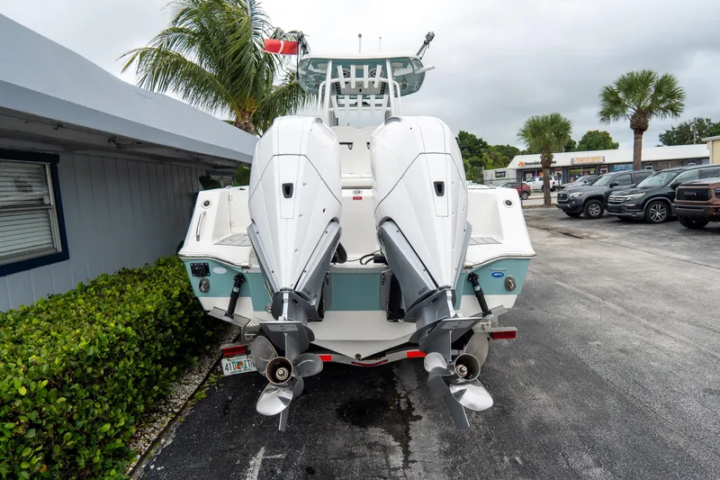 Slide: The Image of 2022 Tidewater 292 CC Adventure boat with dual outboard engines, parked outdoors. - 6