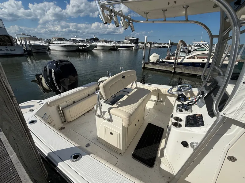 Slide: The Image of 2012 Mako 234 Center Console boat docked at marina under blue sky. - 3