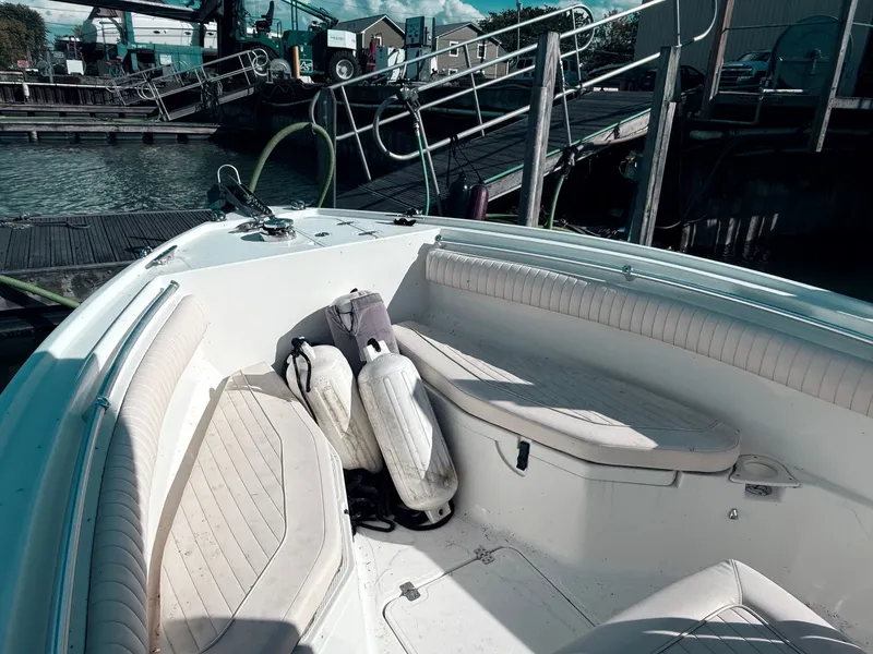 Slide: The Image of 2012 Mako 234 Center Console boat interior at dock, featuring seating and life jackets. - 6