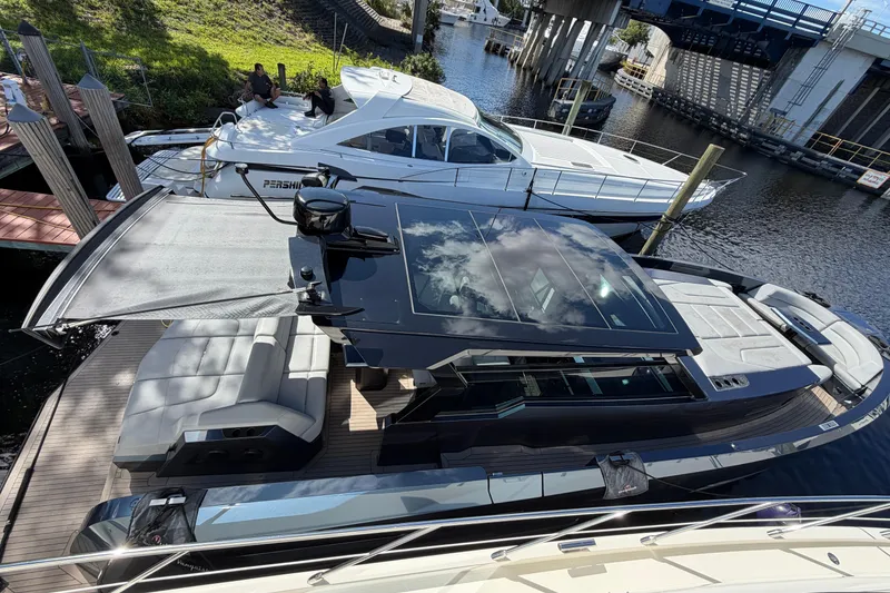 Slide: The Image of 2022 Vanquish VQ45 luxury yacht docked beside another boat, reflecting sky and clouds. - 2
