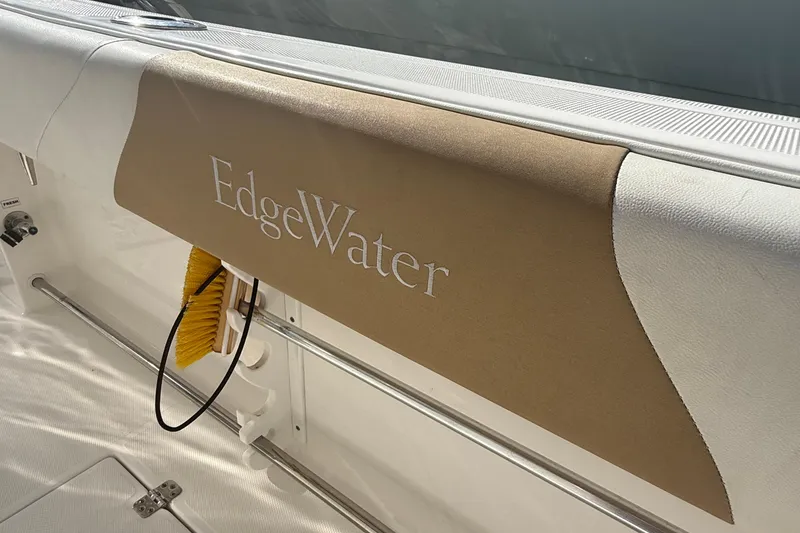 Slide: The Image of Edgewater 280CC boat interior detail, featuring branded upholstery and cleaning brush. - 13