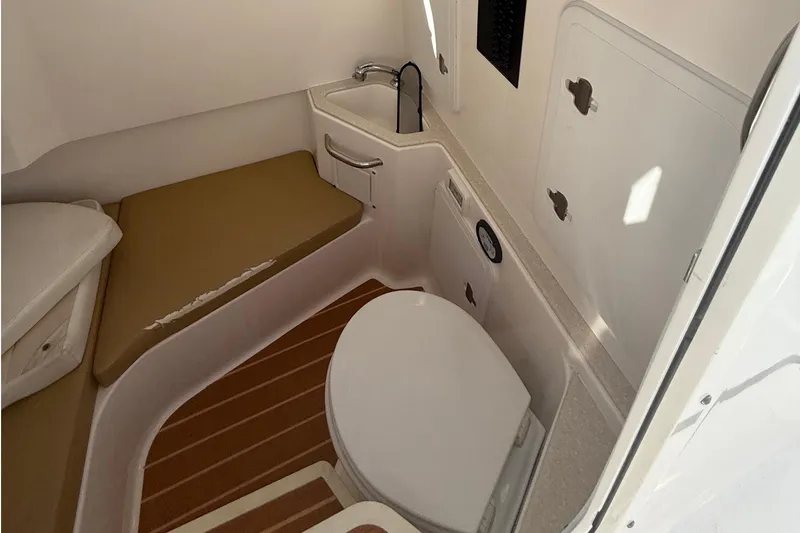 Slide: The Image of Interior of 2016 Edgewater 280CC boat featuring compact bathroom with sink and toilet. - 35