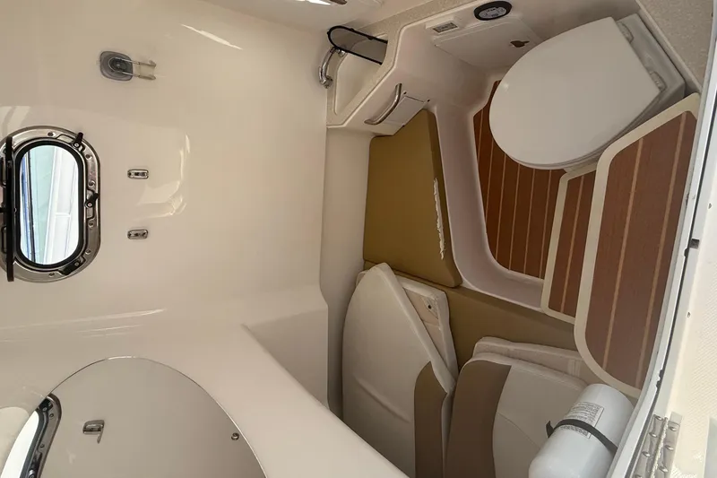 Slide: The Image of Interior of 2016 Edgewater 280CC boat featuring a compact bathroom with a porthole window. - 39