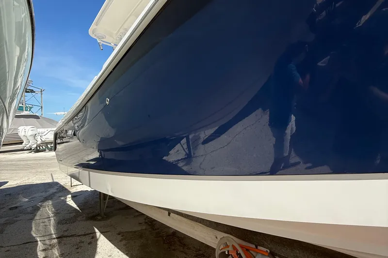 Slide: The Image of 2016 Edgewater 280CC boat with sleek blue hull, docked outdoors. - 53