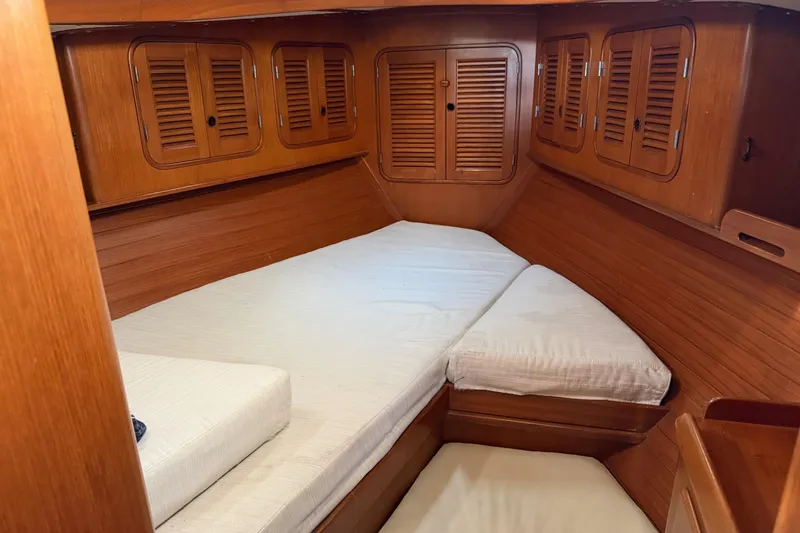 Slide: The Image of Cozy wooden cabin interior of 1985 Mason 33 sailboat with cushioned bed and storage cabinets. - 15