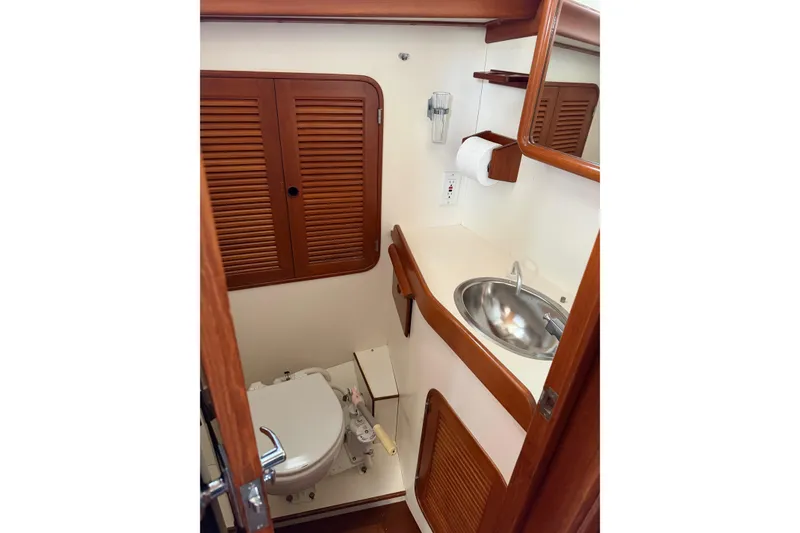 Slide: The Image of 1985 Mason 33 yacht bathroom with wooden cabinets, stainless steel sink, and toilet. - 22