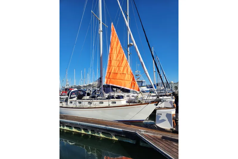 Slide: The Image of Sailboat Mason 33, 1985 model, docked with vibrant orange sail against clear blue sky. - 5