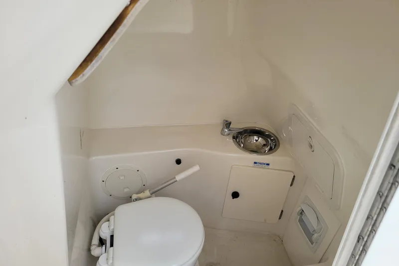 Slide: The Image of 2008 Pursuit C 250 Center Console boat interior with compact marine toilet and sink. - 14