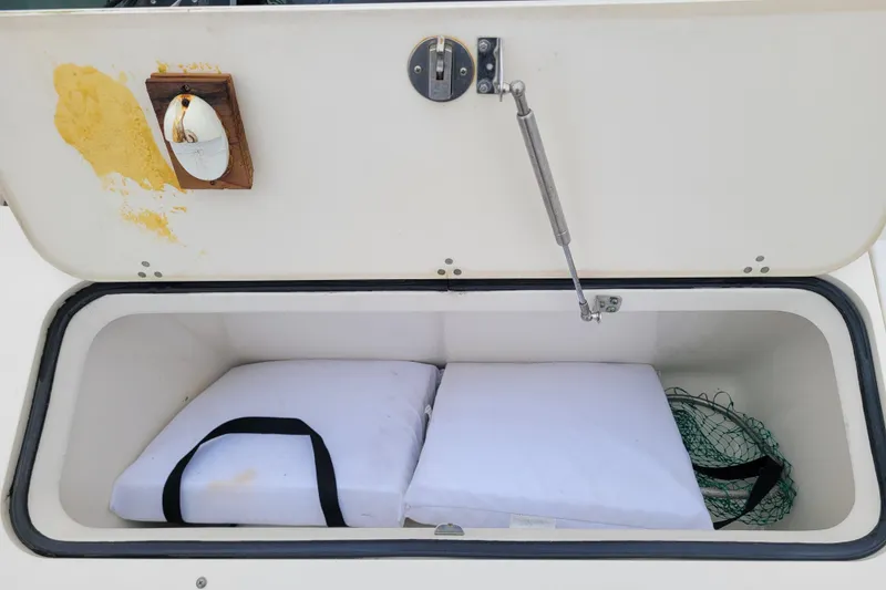Slide: The Image of Open storage compartment on 2008 Pursuit C 250 Center Console boat with cushions and net. - 16