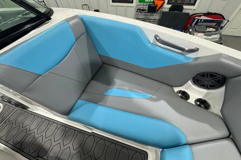 Slide: The Image of 2020 MasterCraft NXT22 boat interior with blue and gray seating, cup holders, and speaker. - 13