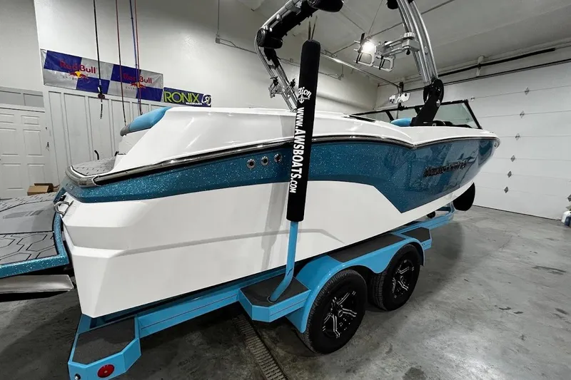 Slide: The Image of 2020 MasterCraft NXT22 boat in a garage, featuring a blue and white design on a trailer. - 2