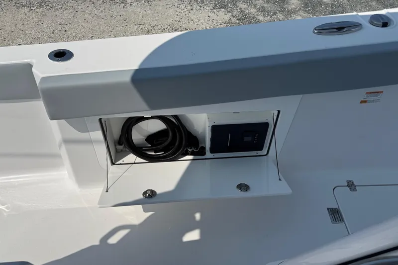 Slide: The Image of 2026 Sportsman Heritage 321 Center Console storage compartment with coiled hose and control panel. - 13