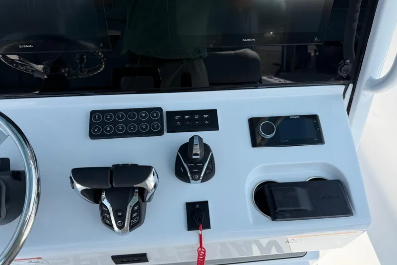 Slide: The Image of Center console controls of 2026 Sportsman Heritage 321 boat with Garmin and Fusion systems. - 22