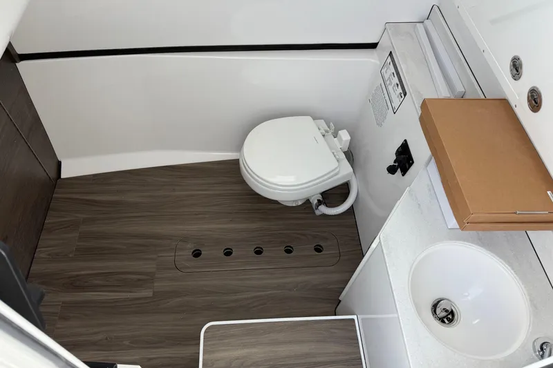 Slide: The Image of 2026 Sportsman Heritage 321 Center Console bathroom with toilet, sink, and wood-style flooring. - 27