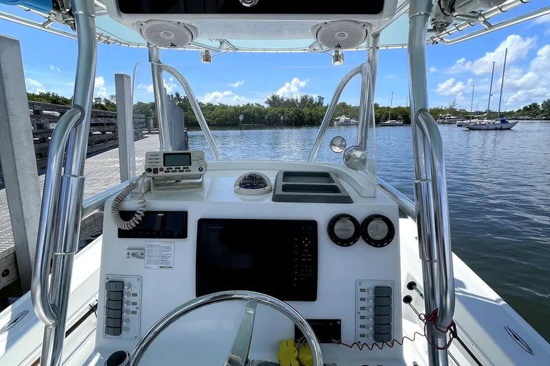 Slide: The Image of 2013 Ocean Master 27 Center Console boat dashboard with navigation equipment, docked by calm waters. - 13
