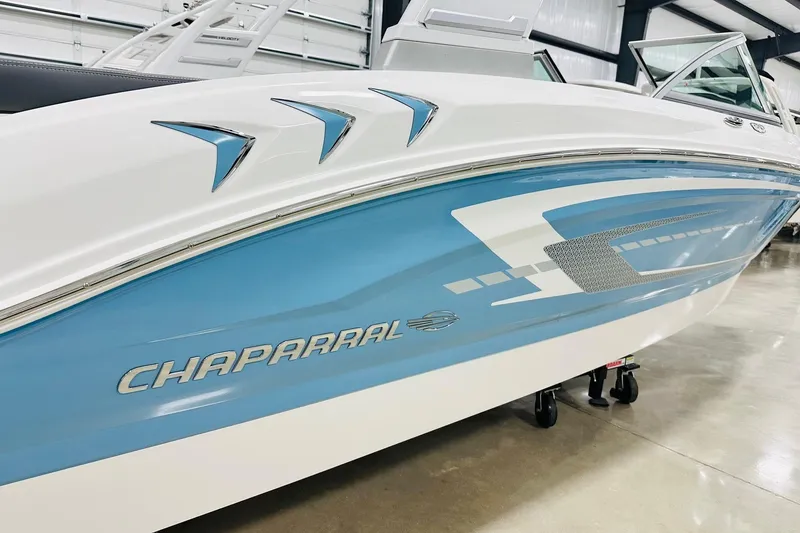 Slide: The Image of 2026 Chaparral 19 SSi OB boat with sleek blue and white design in showroom. - 15